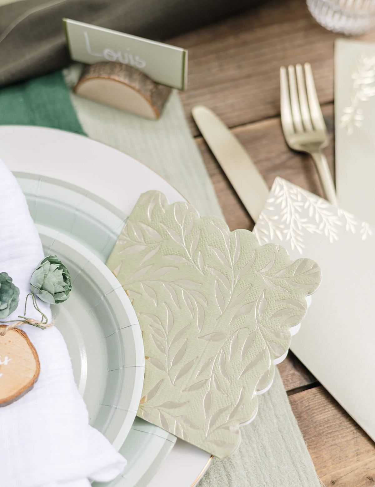Détail de la décoration de table avec les serviettes cocktail en papier à bords festonnés pour fête vert sauge et or