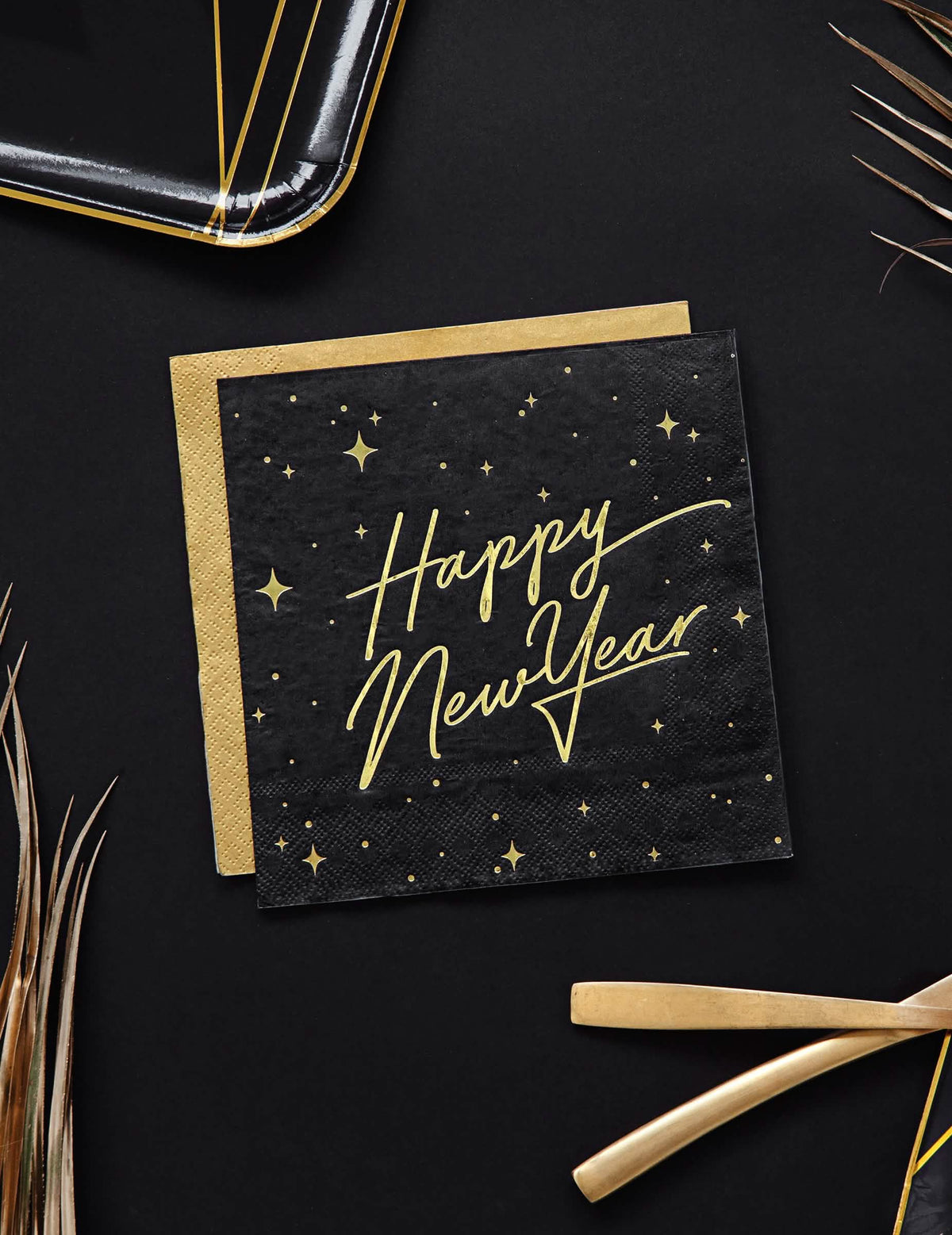 Pohled shora na černo-zlaté papírové ubrousky Happy New Year s hvězdnou dekorací