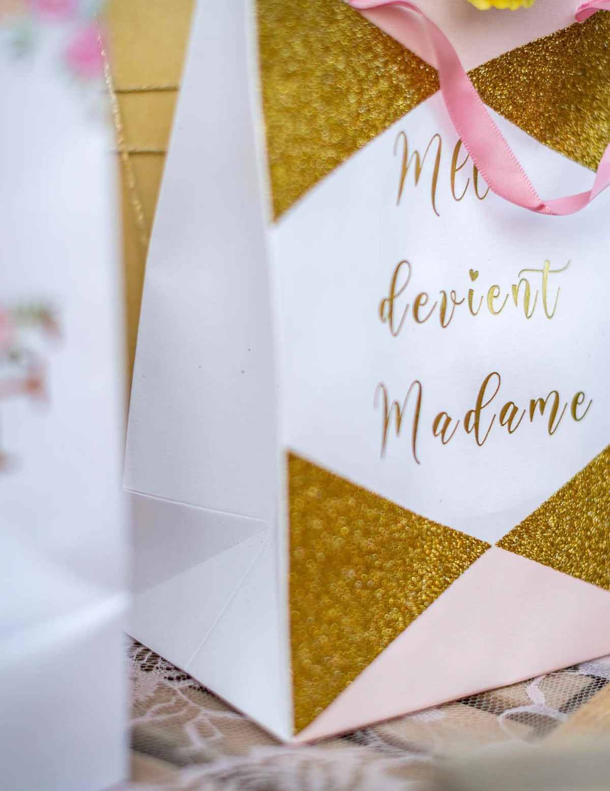 Detailní záběr na třpytivé detaily a nápis na kartonové tašce Mlle devient madame pro budoucí nevěstu