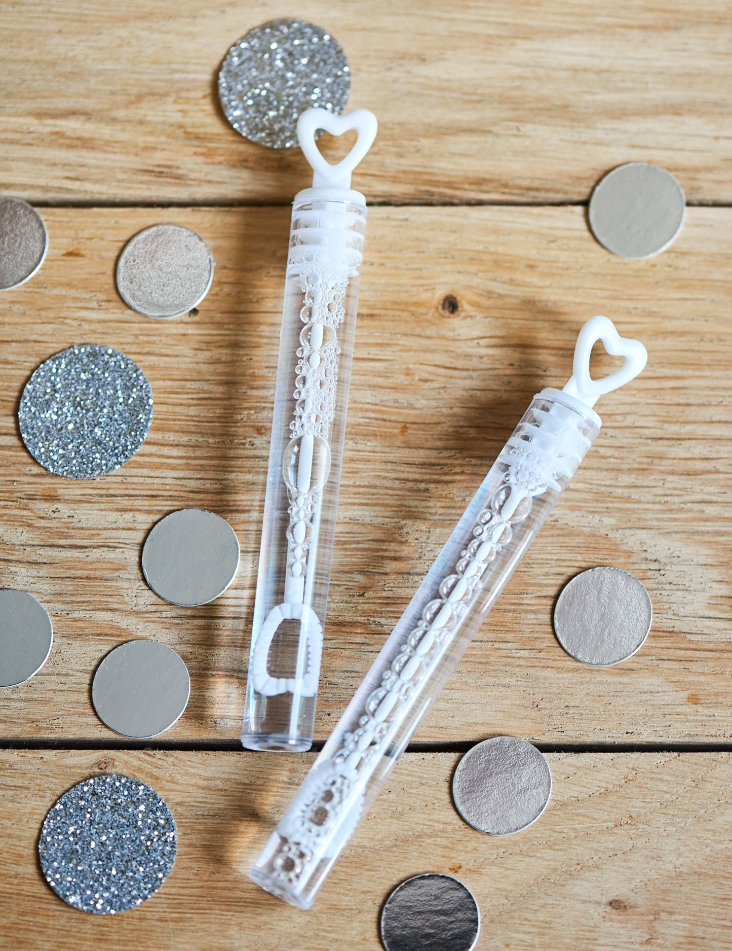 Détail avec confettis des flacons à bulles en forme de coeur pour mariage blanc
