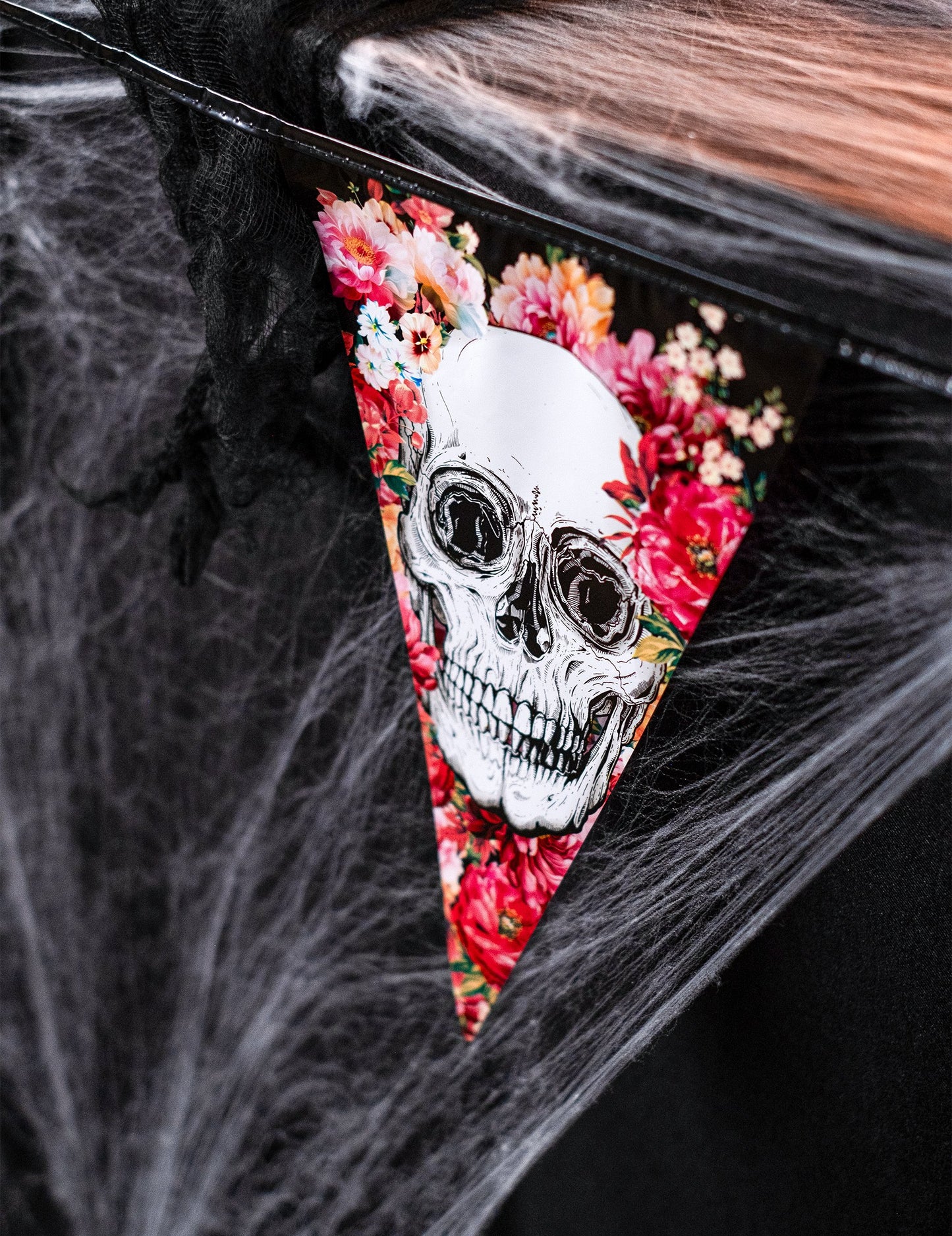 Détail du motif tête de mort et fleurs de la guirlande en plastique squelette fleuri