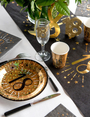 Vue d'ensemble sur une table de fête des gobelets en carton Joyeux Anniversaire pour fête noir et or avec motifs d'étoiles