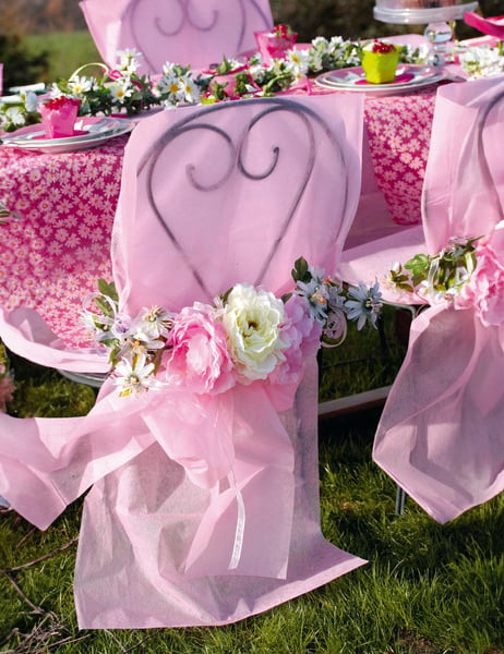 Mise en situation de la housse de chaise premium avec nœud pour décoration de fête rose intissé