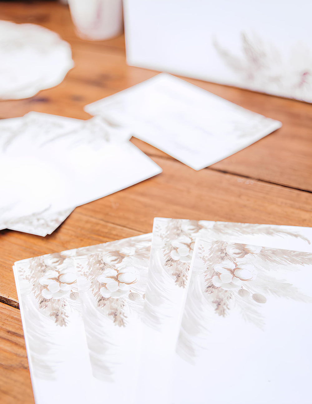 Détail du motif floral des invitations avec enveloppes pampas et fleurs de coton