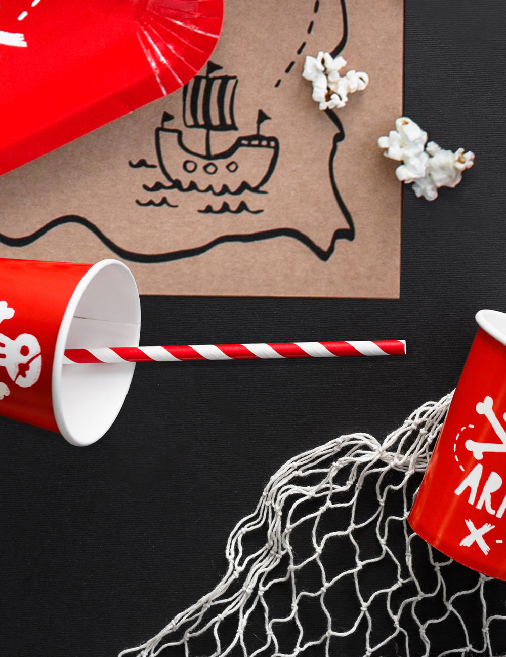 Mise en situation ambiance pirate des pailles en carton rayées pour boissons froides rouges et blanches