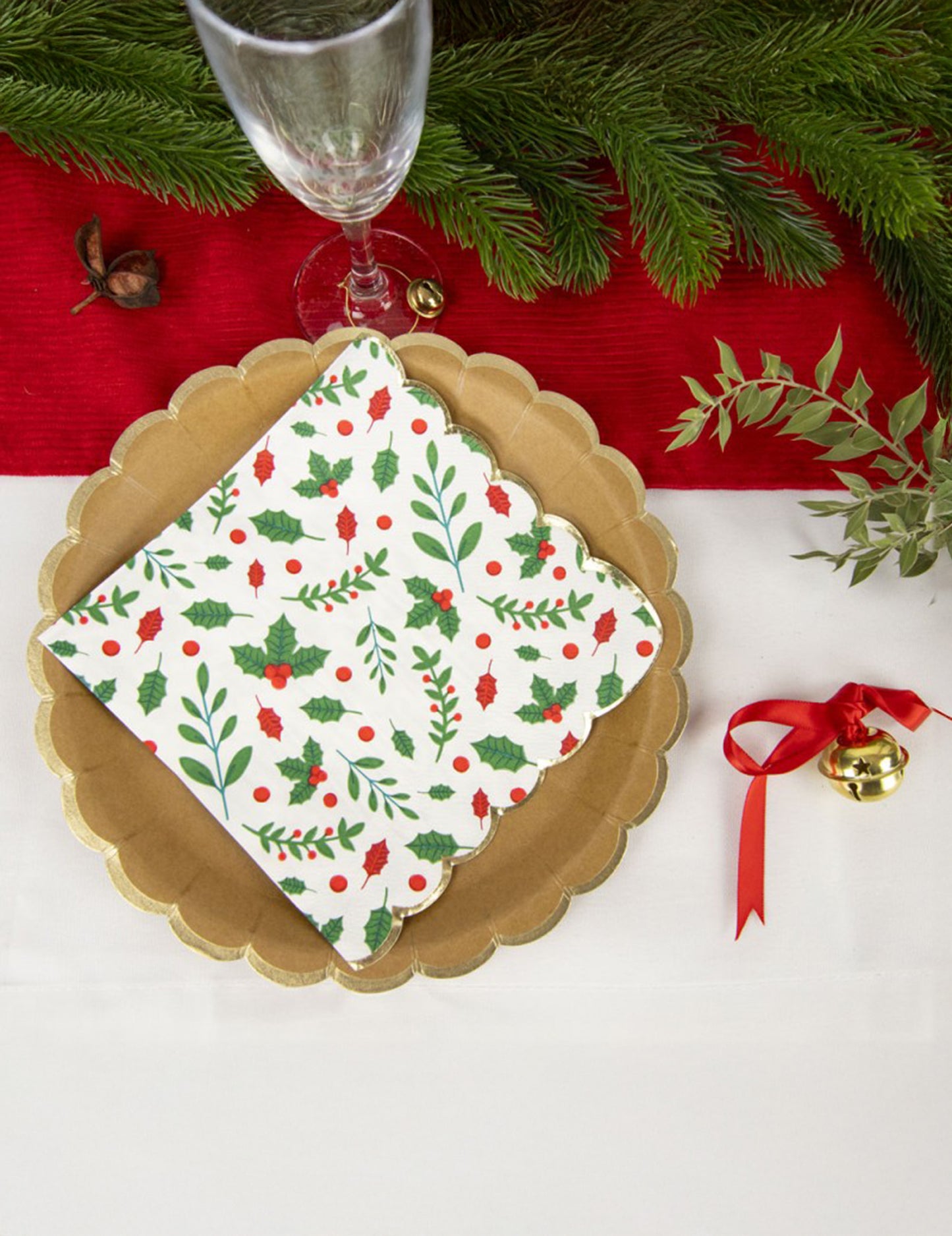 Mise en situation sur une table de fête des serviettes en papier festonnées houx pour Noël