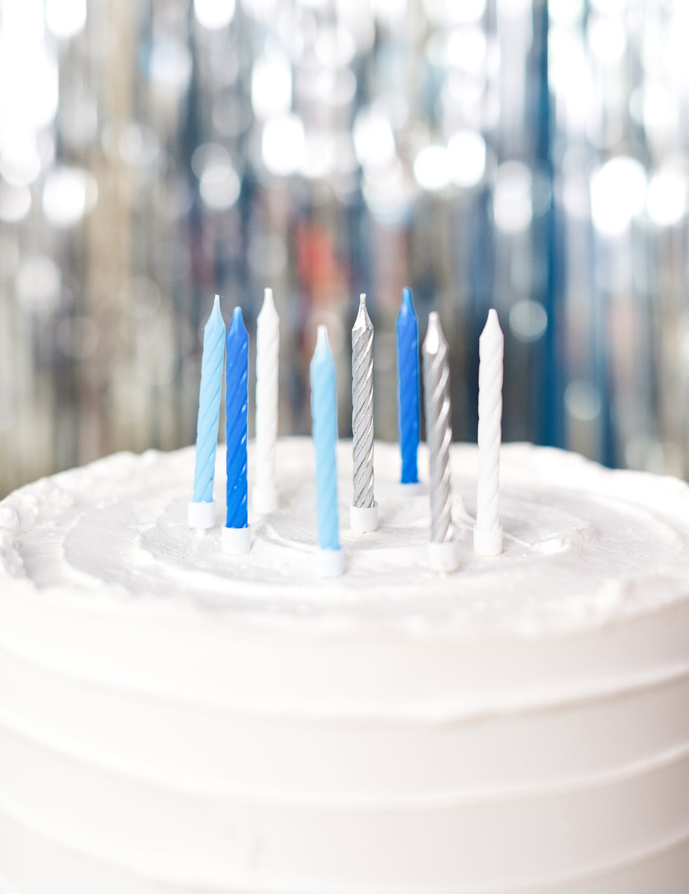 Gros plan sur les bougies d'anniversaire pour fête bleues blanches et argentées torsadées