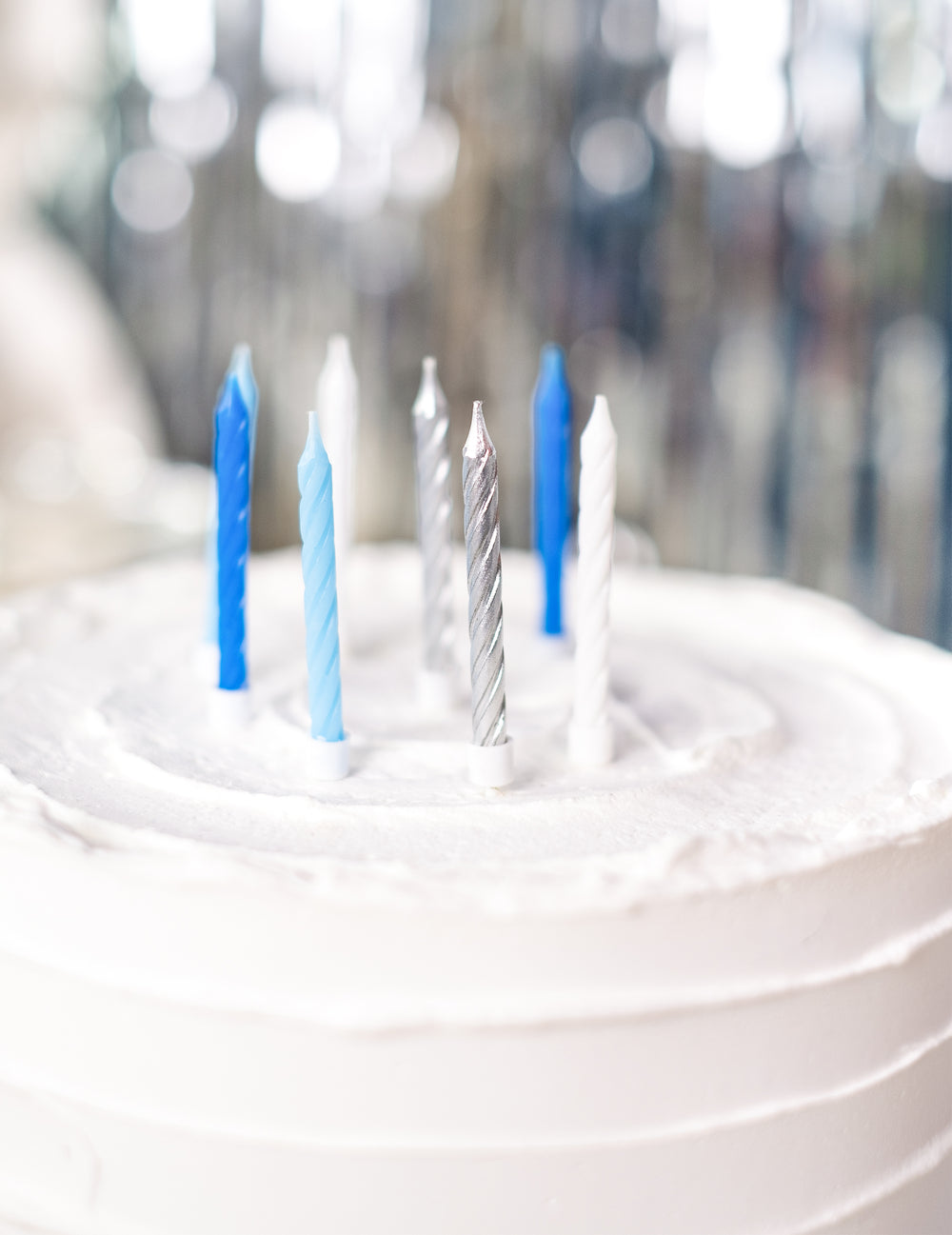 Vue rapprochée sur le gâteau des bougies d'anniversaire pour fête bleues blanches et argentées torsadées