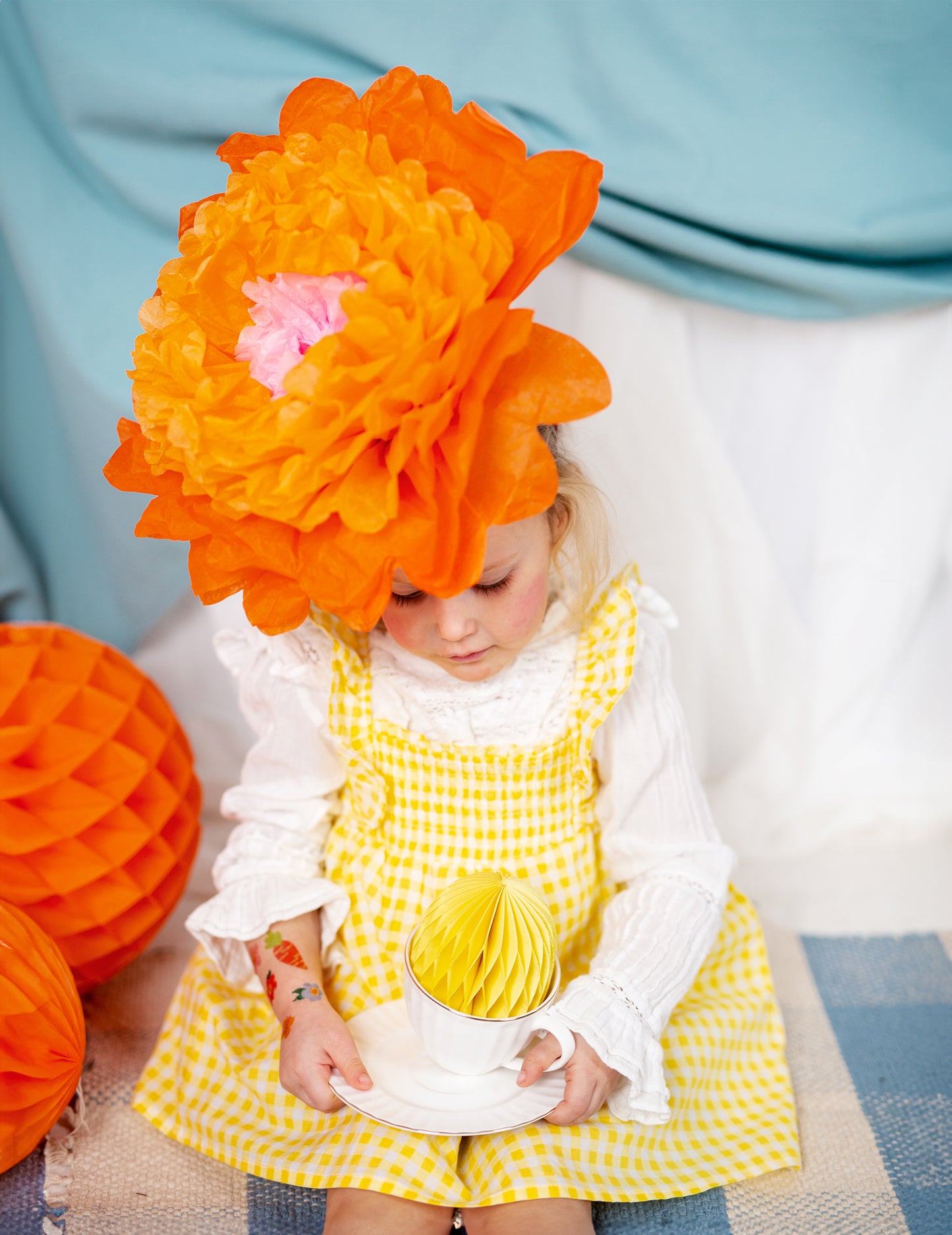 Détail de la fleur orange portée sur la tête des fleurs géantes en papier à suspendre rose jaune et orange