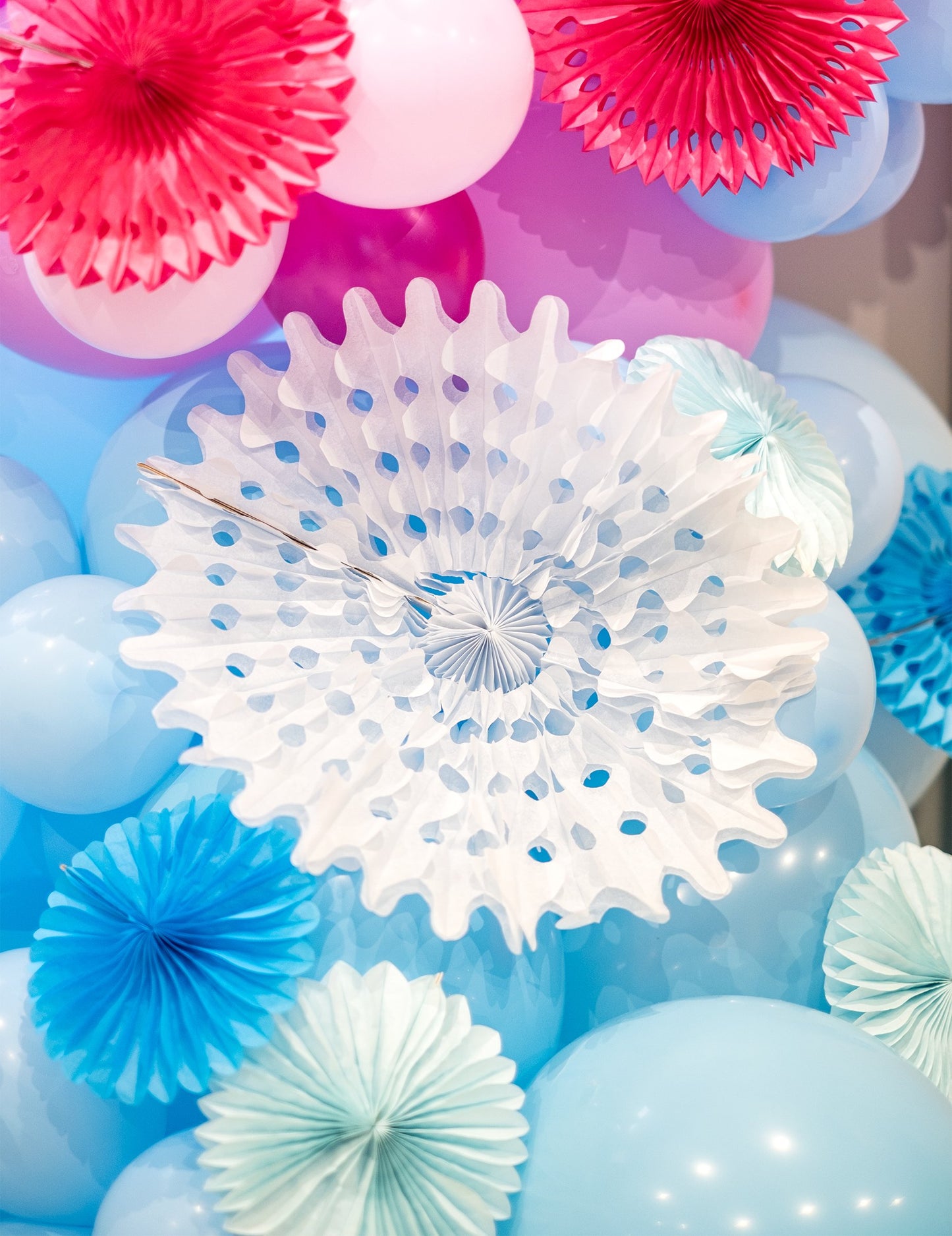Mise en situation avec des ballons des rosaces éventails en papier de décoration pour fête bleu ciel