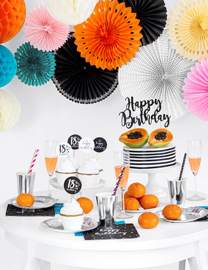 Mise en scène sur une table d'anniversaire des rosaces en papier pour décoration noires et blanches à motifs variés