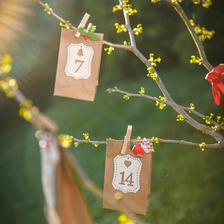 Mise en scène en calendrier de l'Avent des petits sachets kraft pour invités marron avec étiquettes et ficelles blanches