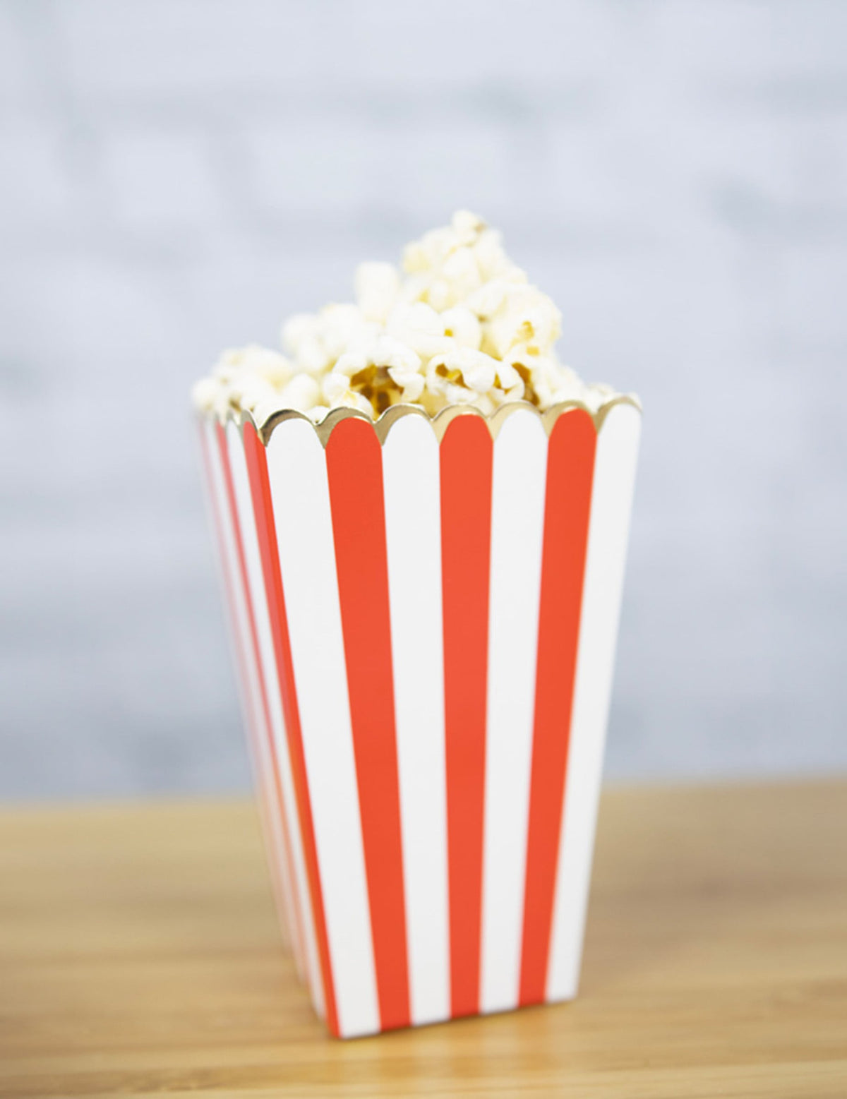 Vue d'une boîte remplie de popcorn des boîtes à popcorn à rayures pour fête rouges et blanches avec liseré doré