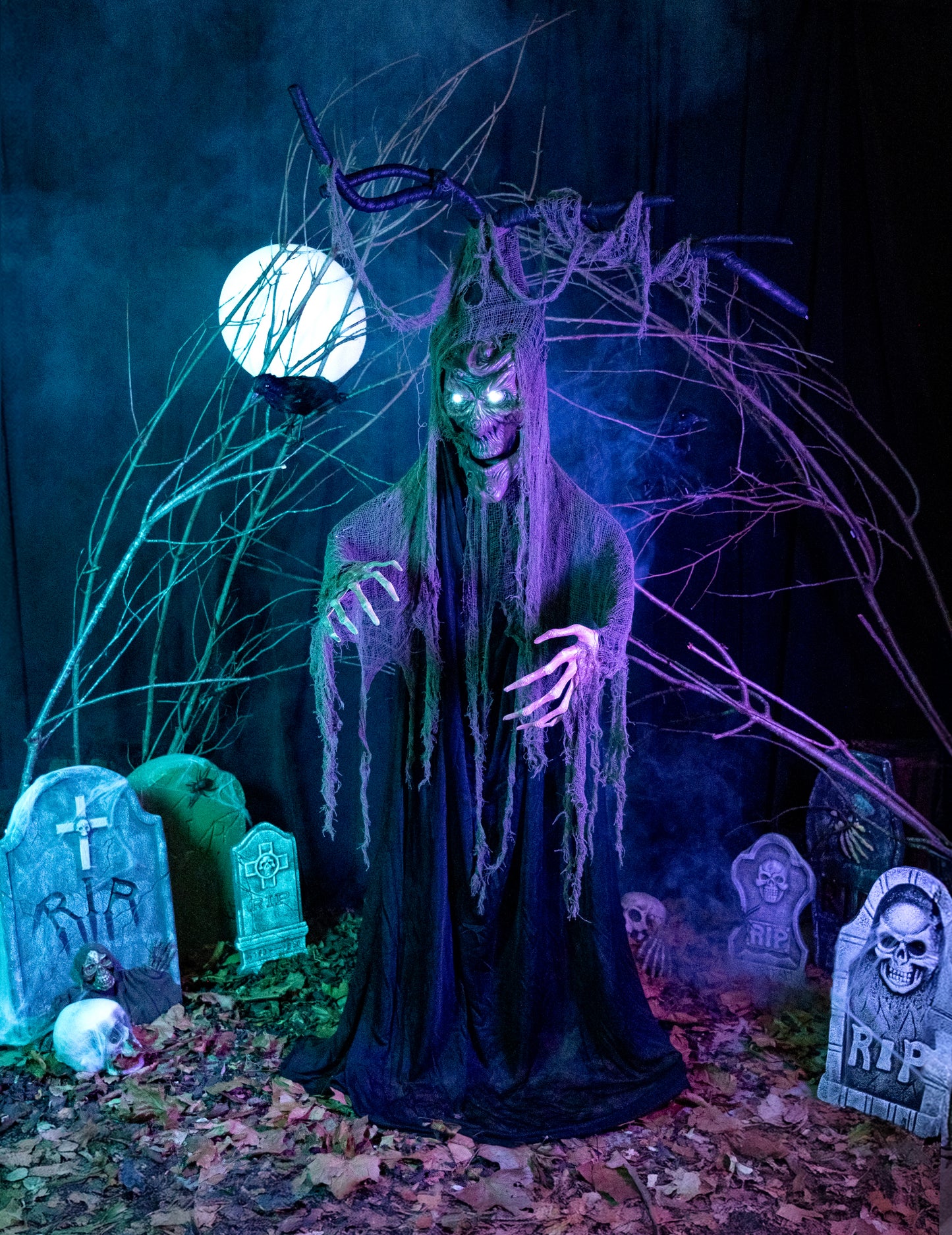 Mise en situation de l'arbre hanté articulé lumineux et sonore Halloween dans un décor de cimetière
