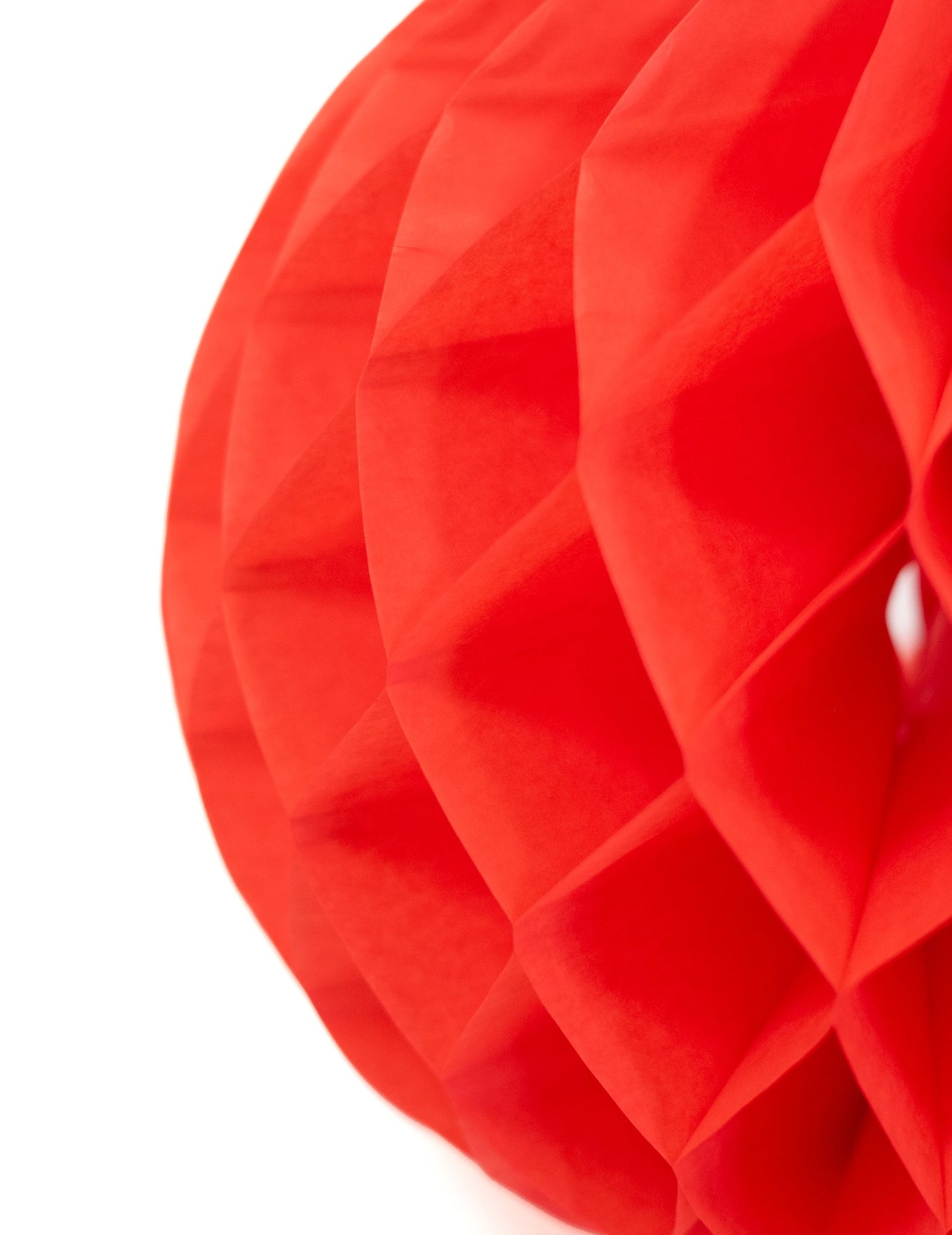 Gros plan sur la structure alvéolée de la boule en papier alvéolé pour décoration rouge