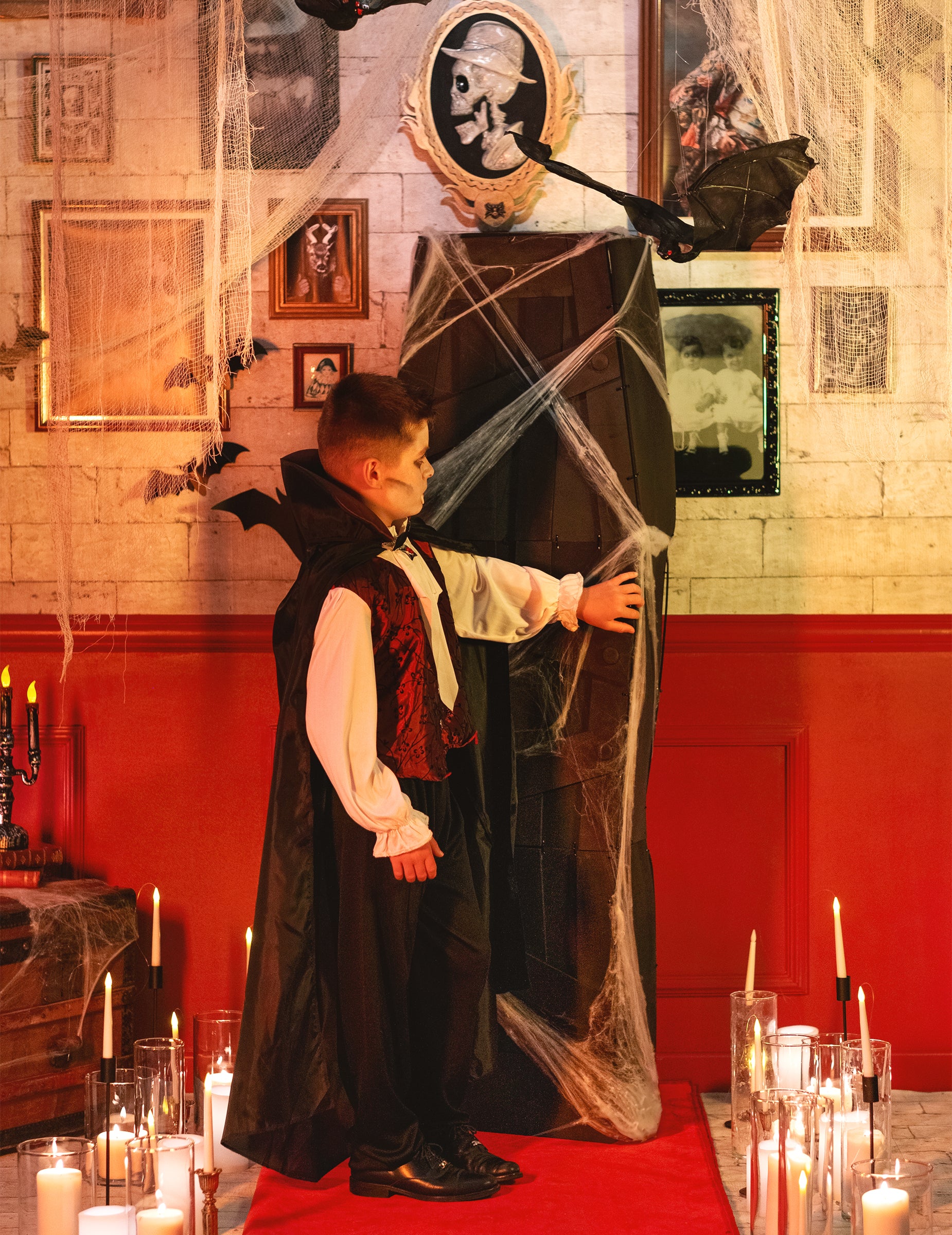 Profilový pohled s dětským upírem u halloweenské rakve na dekoraci s bílou pavučinou