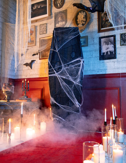 Scéna se svíčkami a kouřem u halloweenské rakve na dekoraci s bílou pavučinou