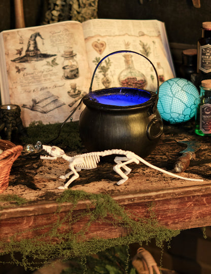 Mise en situation avec grimoire et chaudron de la décoration squelette rat pour Halloween