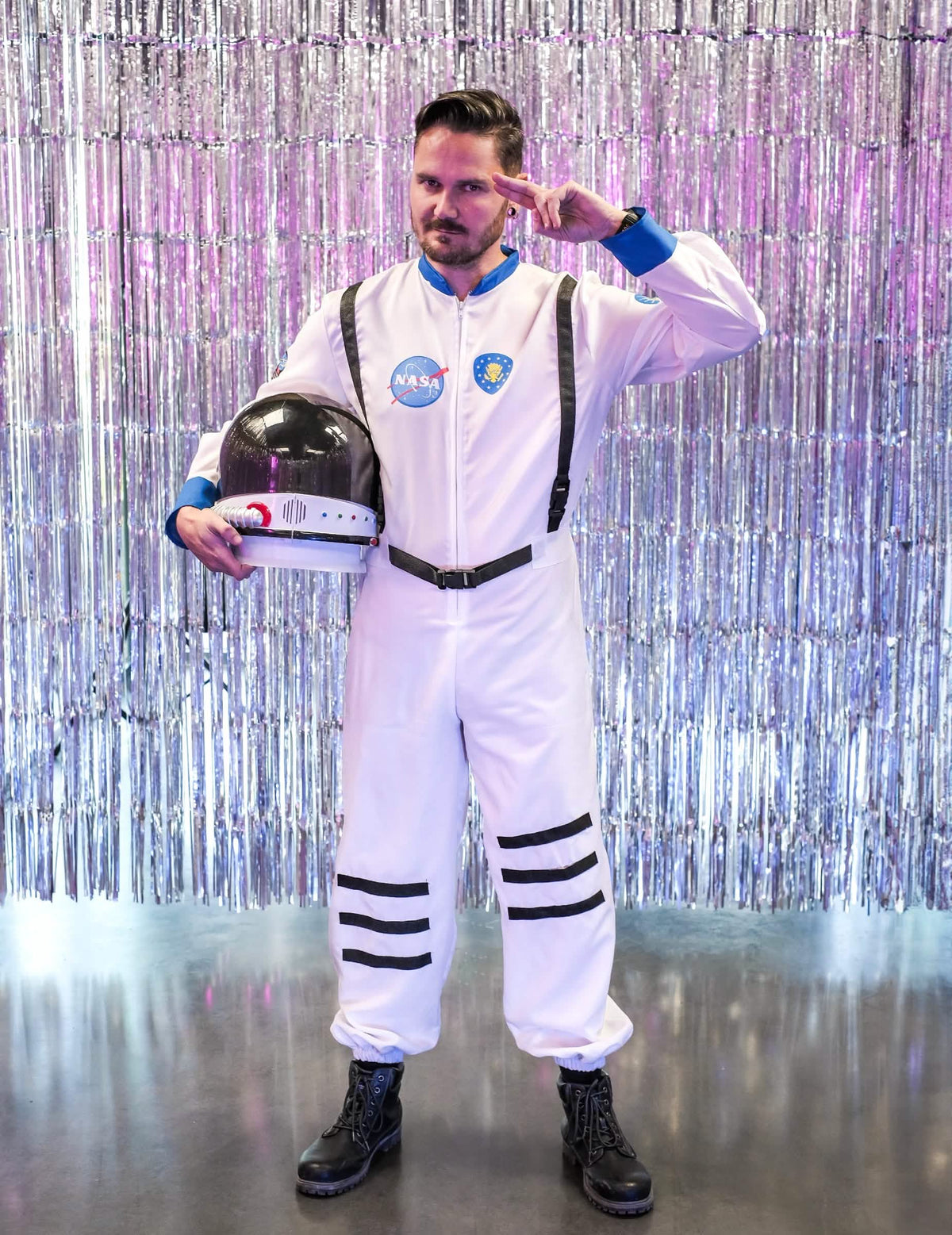 Pozice salutování s helmou pod paží před stříbrná pozadím kostýmu astronauti z vesmíru