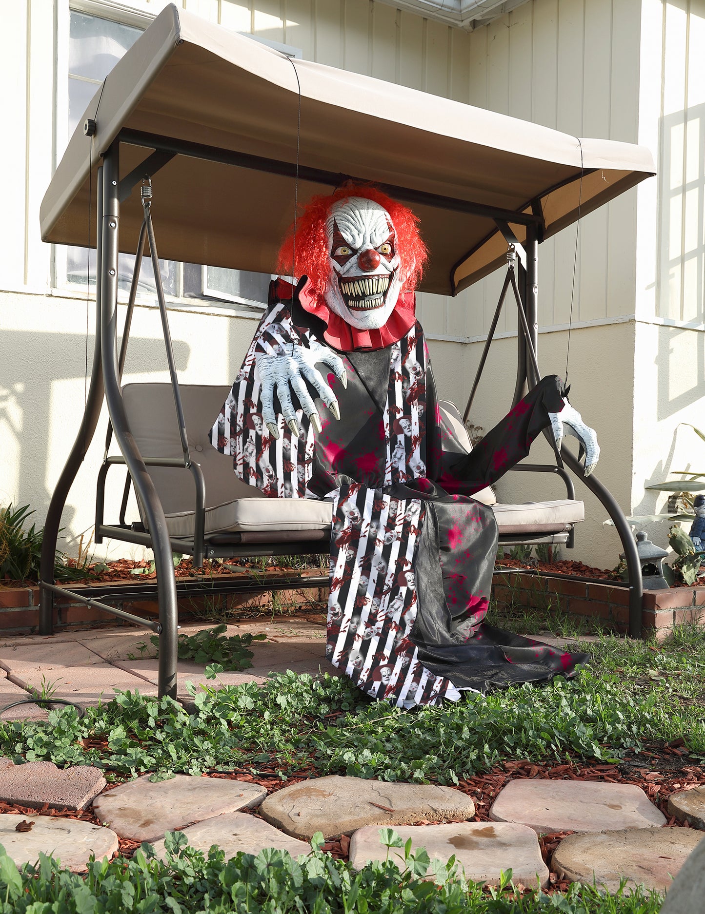 Clown assis sur une balancelle du déguisement clown terrifiant géant 2 en 1