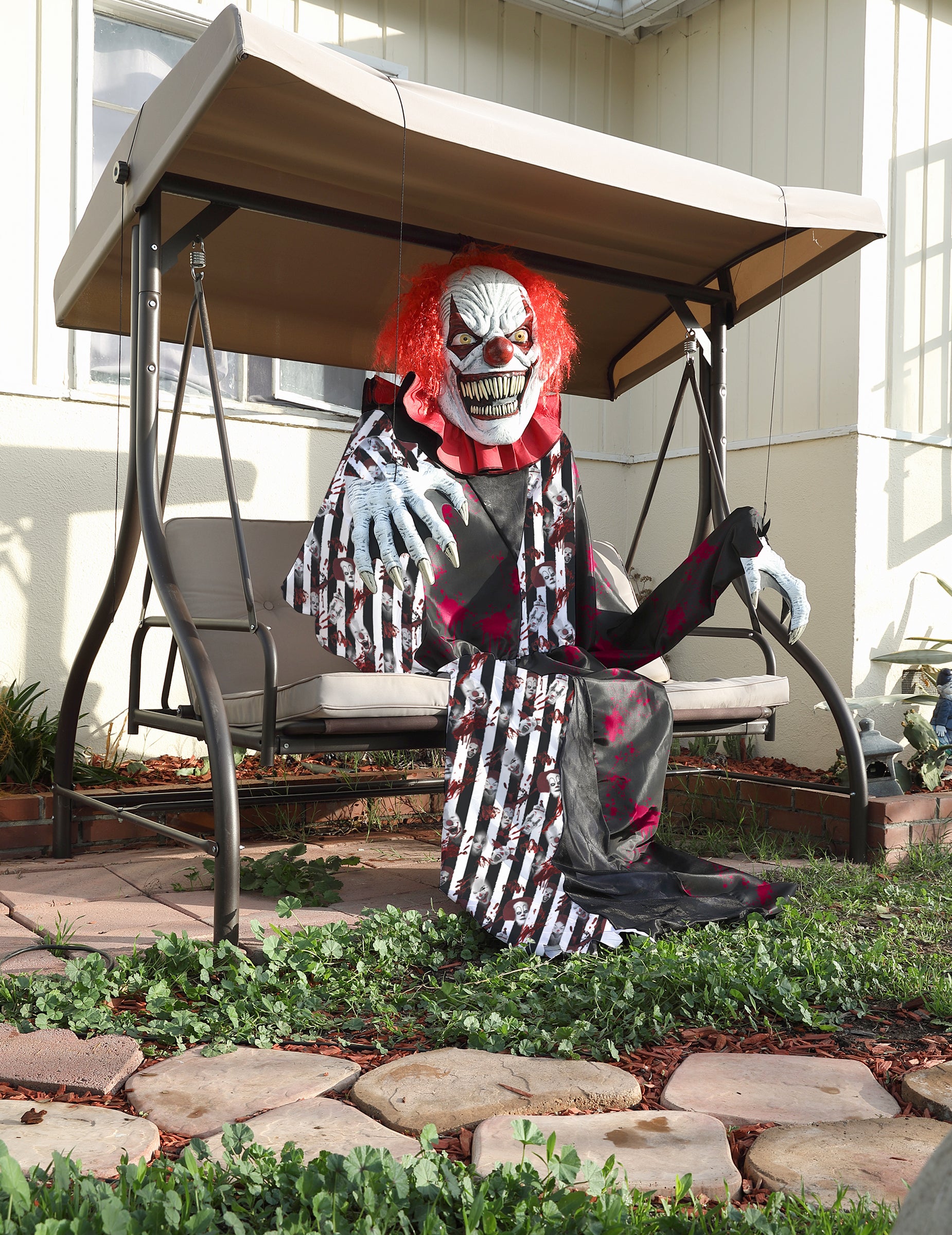 Clown assis sur une balancelle du déguisement clown terrifiant géant 2 en 1