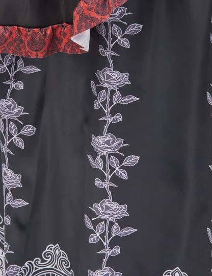 Détail des imprimés de roses blanches et volants rouges du déguisement robe longue Dia de los muertos