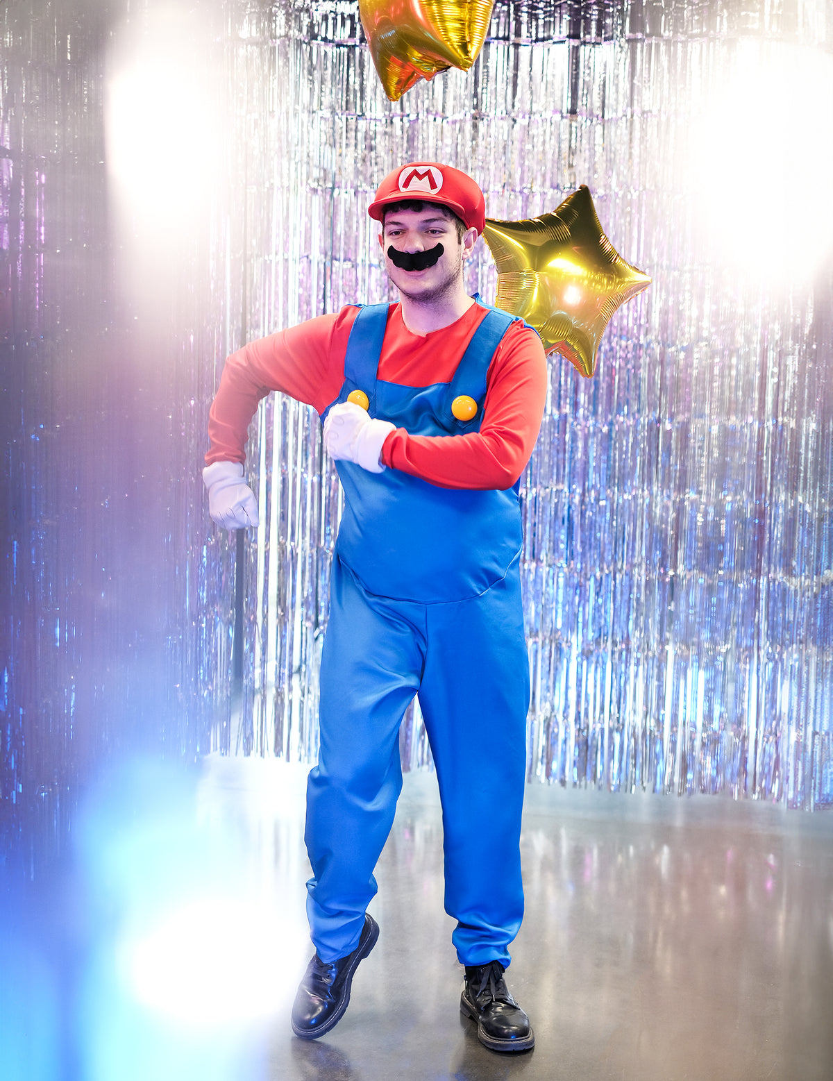 Mise en situation festive avec rideau de fête du déguisement de Mario pour adulte