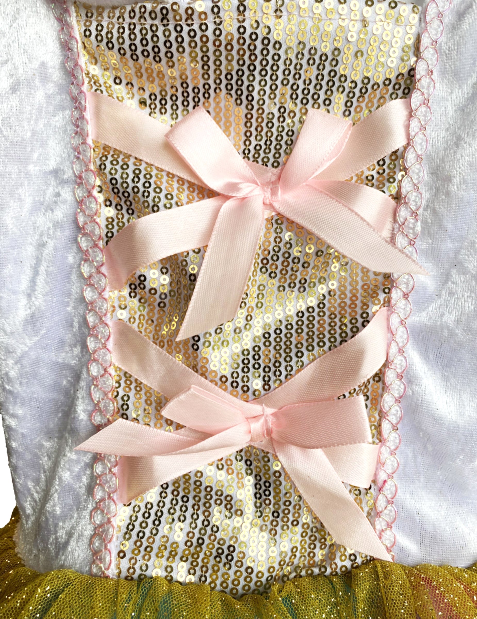 Détail du bustier à sequins dorés et nœuds roses du déguisement Princesse Licorne lumineuse