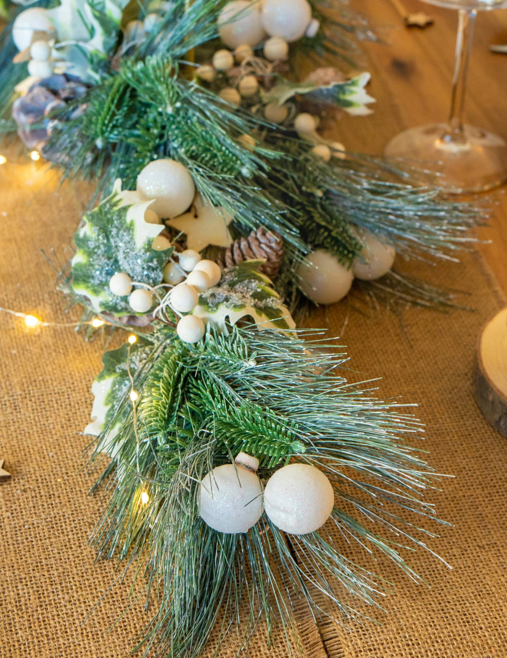 Détail des aiguilles de pin et des boules blanches de la guirlande de Noël feuillage vert et pommes de pin