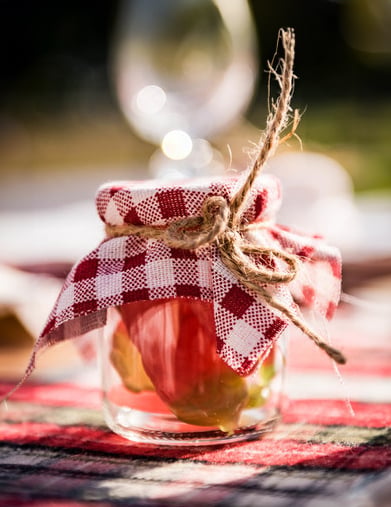 Gros plan sur le couvercle en tissu et le lien en jute du pot en verre style guinguette vichy rouge et blanc